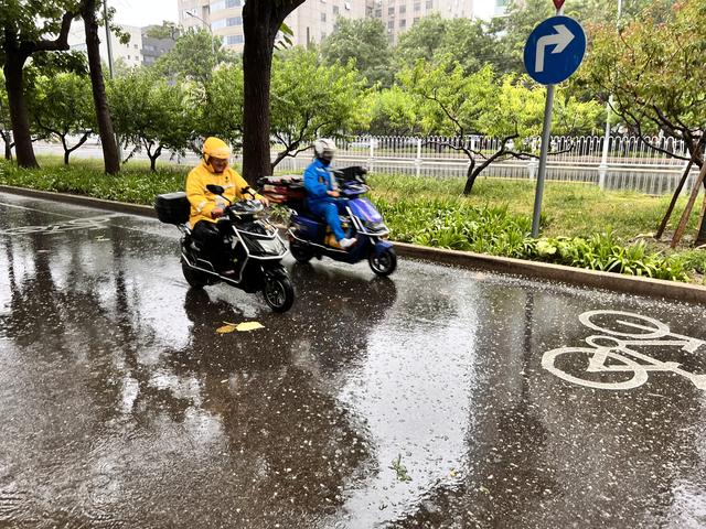 7月30日12时，北京海淀区车公庄西路，外卖骑手冒雨送餐。新京报记者 秦胜南摄